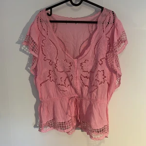 Rosa blus med broderade blommor💗💋🦓 - 💗💋Supersöt rosa blus med broderade blommor och detaljer. Blusen har v-ringning, korta ärmar med volang och knyt i midjan. Materialet är lätt och luftigt, nästan linne-aktigt, perfekt för varma dagar. Blir även superfint med ett linne under. Unik och romantisk, pris kan diskuteras💋💗