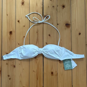 Vit bikiniöverdel - Supersöt vit bikiniöverdel från H&M med broderade små blommor och knyt i nacken. Går att ta av bandet och ha som en bandue bikini💕💕säljer då jag köpte fel storlek och inte hann lämna tillbaka, aldrig använd med prislapp kvar🌸🌸