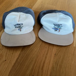Somrig keps från H&M med mesh - Säljer en beige och vit keps från H&M med mörkgrå mesh på sidorna. Framsidan har trycket 'SUMMER DAYS' med en sköldpadda, surfbräda och palm. Perfekt för soliga dagar och chill strandhäng. En är mer använd o går att diskutera om priset :)