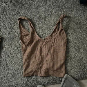 Beige ribbad croppad linnetopp - Säljer en beige croppad linnetopp med ribbad struktur. Toppen har breda axelband och rundad halsringning, perfekt för varma dagar.