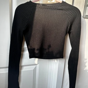 Svart croppad ribbad tröja från Gina Tricot - Säljer en svart croppad långärmad tröja från Gina Tricot. Tröjan är ribbad och har en tight passform med rund halsringning. Perfekt att styla med höga jeans eller kjol. Använt många gånger men fortfarande bra skick ❤️