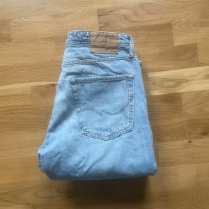 Jack & Jones jeans  - Säljer ett par ljusblå Jack & Jones  jeans med loose fit och raka ben. Klassisk femficksmodell med gylf och knapp. Midjemått 33 och längd 32. Perfekta för en avslappnad stil.