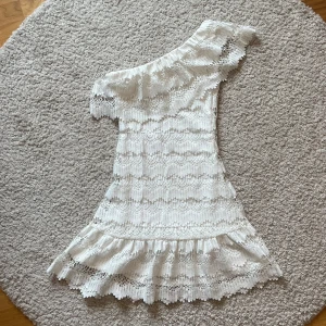 Vit spetsklänning med volang  - Så himla snygg och unik studentklänning från Dry Lake! Med spets, volangdetaljer och oneshoulder-modell🥹🙏🏼