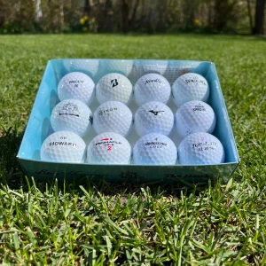 Låda med blandade Florida bollar 12 pack - Säljer en låda med 12 vita golfbollar av olika märken, inklusive Bridgestone och Pinnacle. Bollarna har olika tryck och logotyper, och levereras i en blå kartong. Perfekt för golfentusiasten som vill ha variation på banan.