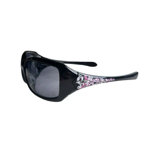 Oakley Liv breast cancer awareness solglasögon - Stora svarta solglasögon med breda skalmar och coolt rosa och vitt mönster på sidorna. Glasen är mörka och bågarna har en glansig finish. Perfekt för dig som vill sticka ut med en trendig accessoar. Finns märken på glaset, se bilder