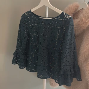 Mörkgrön spetsblus med volangärmar från Part Two - Säljer en mörkgrön blus från Part Two i genombruten spets med vackert mönster. Blusen har trekvartsärmar 