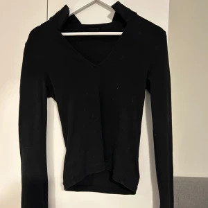 Svart v-ringad långärmad topp - Säljer en svart långärmad topp med v-ringning. Enkel och stilren design som passar till många olika outfits. Perfekt basplagg för garderoben.