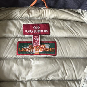 Svart superlätt dunjacka från Parajumpers - Säljer en svart superlätt dunjacka från Parajumpers, modell Anchorage. Jackan har klassisk quiltad design, lång ärm och tydlig logotyp-patch på ärmen. Perfekt för dig som vill ha en lätt och smidig jacka med snygg look.Den är i M men är liten så den passar folk som har S