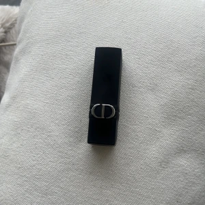 Rouge Dior läppstift 626 - Säljer ett Rouge Dior läppstift i nyansen 626. Hylsan är svart med silverdetaljer och den klassiska CD-loggan. Färgen är en varm, brunrosa ton som passar perfekt till vardags. Lyxig och elegant design från Dior.  Kommer utan förpackning, oanvänd och otestad, om du köper fler av dessa läppstift kan jag tänka mig bättre pris. Rensning inför flytt. Vissa märken på själva skalet på läppstiftet kan förekomma då jag förvarat alla i samma låda 