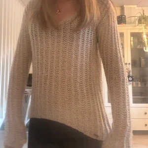 Beige stickad tröja med v-ringning - Säljer en beige stickad tröja med v-ringning och lång ärm. Tröjan har ett ribbat mönster och är mjuk och skön, perfekt för lager-på-lager. Passar till både jeans och kjol.