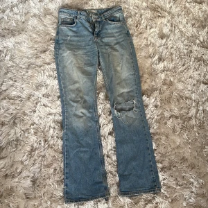 Blå jeans från Perfect Jeans - Säljer ett par klassiska blå jeans från Perfect Jeans i storlek 34. Jeansen har bootcut-modell, normal passform och slitningar på ena benet för en trendig look. Perfekta till vardags med snygg tvätt och femficksdesign.