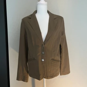 Olivgrön kavaj med knappar - Snygg olivgrön kavaj med tre silverfärgade knappar framtill