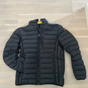 Lättviktsjacka från parajumper - Säljer en svart lättvikts pufferjacka från Parajumpers med hög krage och dragkedja framtill. Jackan har en bröstficka med dragkedja och klassisk patch på ärmen. Perfekt för kyliga dagar. Ny pris ligger runt 4000 kr.