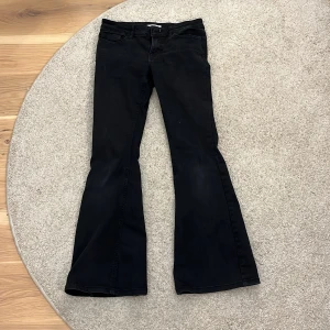 Svarta bootcut jeans - Säljer ett par svarta bootcut jeans med lågmidja klassisk femficksdesign. Byxorna har utsvängda ben och normal passform upptill. Perfekta för dig som gillar en retrostil med moderna vibbar.