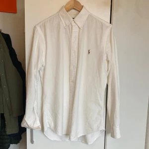 Vit Oxford skjorta från Ralph Lauren - Vit Oxford skjorta från Ralph Lauren. Skjortan har slim fit-passform och är i super skick, något liten på mig därav säljer jag. Priset kan sänkas något vid snabb affär.