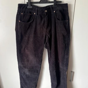 Svarta manchesterbyxor - Säljer ett par svarta manchesterbyxor med klassisk femficksdesign och raka ben. Byxorna har normal passform och stängs med knapp och dragkedja. Perfekta för dig som gillar en tidlös och stilren look.