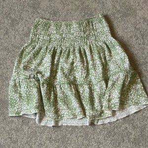 Grön blommig kortkjol från Gina Tricot - Supersöt grön kjol från Gina Tricot med vitt blommönster. Använd bara några fåtal gånger 