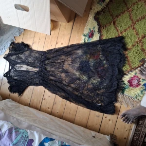 Svart spetsklänning med kort ärm - Säljer en svart långklänning i transparent spets med korta ärmar och v-ringning. Klänningen har ett romantiskt och elegant uttryck med fina spetsdetaljer och markerad midja. Perfekt för dig som vill sticka ut.