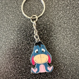 Nyckelring med Ior från Nalle Puh - Söt nyckelring med Ior från Nalle Puh. Ior är blå med rosa inslag på öron och mage samt beige ansikte. Perfekt accessoar för att piffa upp nyckelknippan eller väskan.