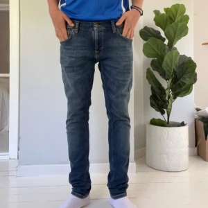 Blå jeans från Nudie Jeans - Säljer ett par klassiska blå jeans från Nudie Jeans med snygga detaljer på bakfickorna och dragkedja i gylfen. Jeansen har normal passform och raka ben, perfekt för en avslappnad stil. Svin bra skick, model terry! Storlek 32/32, hojta vid frågor!
