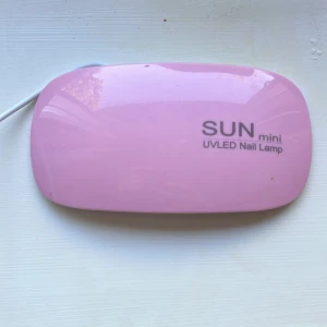 Rosa UVLED-lampa för naglar SUN mini - Säljer en rosa UVLED-lampa för naglar från SUN mini. Perfekt för att härda gel- och shellacklack hemma. Kompakt design med utfällbara ben och USB-sladd. Fyra LED-lampor undertill för jämn belysning. Enkel att använda och smidig att ta med.