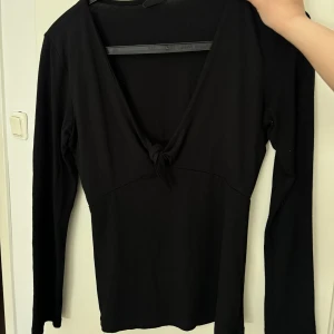 Svart långärmad topp med knyt framtill - Säljer en svart långärmad topp med  v-ringning och knyt framtill. Toppen är tight i modellen och passar perfekt till många olika tillfällen. Ger mycket Elena Gilbert vibes.