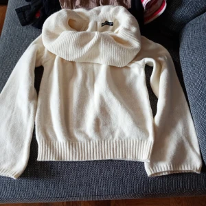 Vit stickad polotröja från SHEIN stl L - Säljer en krämvit stickad polotröja från SHEIN med bred polokrage och långa ärmar. Tröjan har ribbade muddar vid ärmslut och nederkant, perfekt för kyliga dagar. Snygg och enkel att matcha med olika outfits.