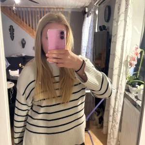 Vit stickad tröja med svarta ränder - Säljer en vit stickad tröja med svarta horisontella ränder. Tröjan har lång ärm, rund halsringning och ribbade muddar vid ärmslut och nederkant. Perfekt för en avslappnad och stilren look.(pris går att diskutera)