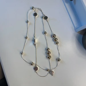 Långt halsband med stora silverfärgade kulor - Säljer ett långt halsband med stora och små silverfärgade kulor samt runda plattor. Köpte den på Ioaku!