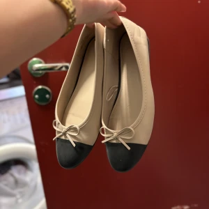 Beige ballerinaskor med svart tå och rosett - Snygga ballerinaskor i beige med svart tå och en liten rosett framtill. Köpte dem för två månader sedan, men har bara använt dem tre gånger. Fint skick🥰