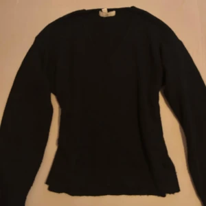 Svart långärmad tröja - Säljer en stilren svart tröja med v-ringning och långa ärmar. Perfekt för kyligare dagar och enkel att matcha med olika outfits.