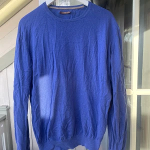 Blå tröja från Massimo Dutti - Säljer en stilren blå tröja från Massimo Dutti. Tröjan har en klassisk rund halsringning och långa ärmar. Perfekt för en avslappnad men ändå elegant look. Lite slitet runt halsen och därmed en lägre pris