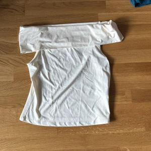 Vit offshoulder topp - Säljer en stilren vit offshoulder topp med lång ärm. Perfekt för en elegant och modern look. Passar bra till både jeans och kjol. Ett måste i garderoben för den som gillar minimalistisk stil.