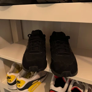 Svarta sneakers från Adidas - Säljer ett par svarta sneakers från Adidas. Skorna har en klassisk design med snörning och är tillverkade i syntetmaterial. Perfekta för en stilren look.