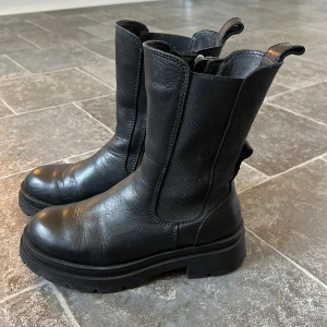 Svarta Canada Snow boots med dragkedja - Snygga svarta boots i skinn från Canada Snow med dragkedja på sidan. Insidan klädd i ull för värmens skull. De har en robust sula och är perfekta för både höst och vinter. Stilrena och enkla att matcha med olika outfits. Min favorit va att ha dom till klänning och leggings 👍🏻Dock för små för mig så dom kommer inte till användning. 