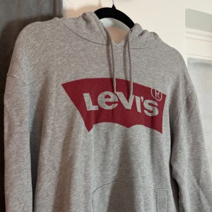 Levi’s hoodie  - !KOLLA BIO INNAN KÖP!    Säljer en klassisk grå hoodie från Levi's med röd logga på bröstet. Storlek L men passar M och S. Fler bilder kan erbjudas!