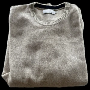 Beige tröja från Casual Friday - Säljer en stilren beige tröja från Casual Friday. Tröjan har en rund halsringning och är tillverkad i ett mjukt material som passar perfekt för kyligare dagar. Perfekt för en avslappnad look.