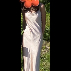 Champagnefärgad klänning från Boohoo - Säljer en elegant champagnefärgad klänning från Boohoo. Klänningen har en slät yta och smala axelband. Den har en vacker drapering framtill. Perfekt till balen. Har bara använt en gång. Jag är 165 och brukar ha xs