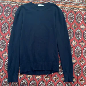 J. Lindeberg ulltröja - Säljer en stilren mörkblå ulltröja från J. Lindeberg. Tröjan har långa ärmar och en klassisk rund halsringning. Perfekt för kyligare dagar och enkel att matcha med olika outfits.