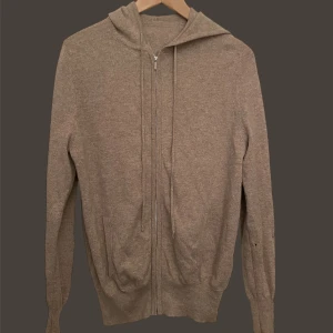 Soft goat - Säljer en beige hoodie med dragkedja och huva. Tröjan har långa ärmar och är tillverkad i ett mjukt material. Perfekt för en avslappnad stil. Hör av dig vid intresse!