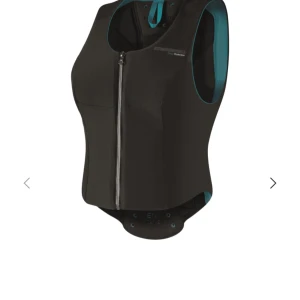 Svart väst med dragkedja - Snygg svart väst med dragkedja och turkos insida. Västen har en tight passform.