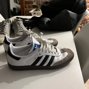 Adidas Samba i vitt och svart - Klassiska Adidas Samba sneakers i vitt med svarta ränder och grå detaljer. Använda max 5 gånger. 