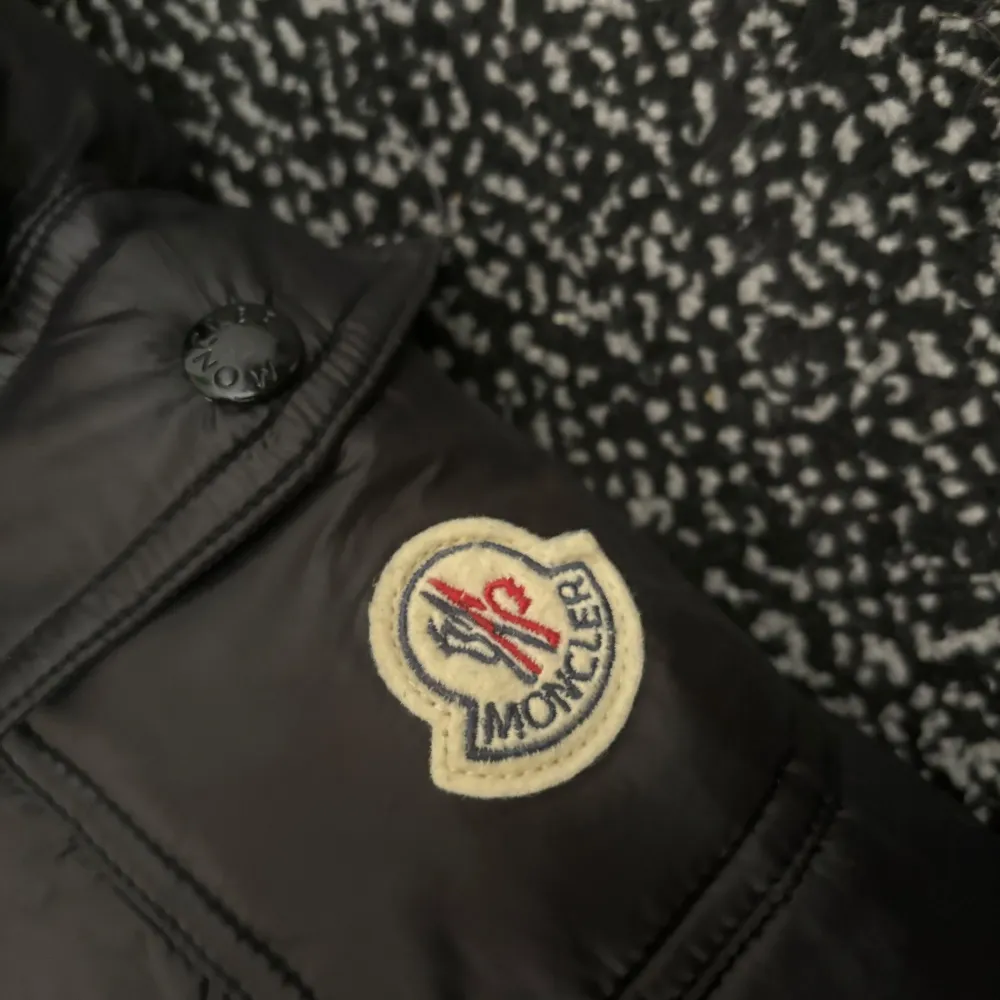 Säljer en snygg svart pufferjacka från Moncler. Jackan har en quiltad design med dragkedja och huva. Perfekt för kyliga dagar med sin stilrena look och varma fyllning.. Takit.