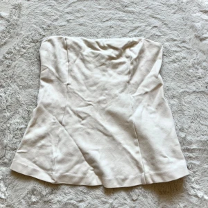 Beige topp  - Säljer en stilren beige topp med en enkel och elegant design. Toppen har en figurnära passform och är perfekt för både vardag och festliga tillfällen. Den är gjord i ett mjukt och bekvämt material.