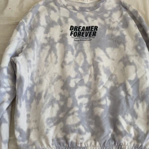 Tie-dye sweatshirt med text - Säljer en cool tie-dye sweatshirt från H&M med texten 'DREAMER FOREVER' på bröstet. Tröjan har en avslappnad passform och är perfekt för en chill dag. Den har långa ärmar och en elastisk nederkant.