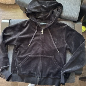 Svart velour hoodie från Juicy Couture - Säljer en svart velour hoodie från Juicy Couture med dragkedja och huva. Tröjan har en klassisk design med ribbade muddar och en praktisk ficka framtill. Perfekt för en avslappnad stil. 😊 pris går att diskuteras.