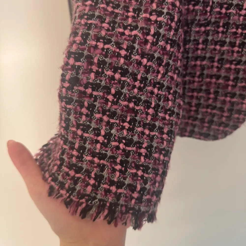 Snygg rutig kavaj i rosa och svart från Kello. Kavajen har en klassisk passform med fransiga detaljer vid ärmslut och krage. Perfekt för att ge din outfit en chic touch.. Takit.