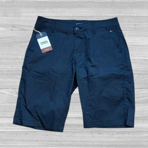 Tommy Hilfiger shorts - Snygga mörkblå shorts från Tommy Hilfiger med diskret mönster. De har en knapp och dragkedja framtill samt fickor både fram och bak. Perfekta för en stilren look.