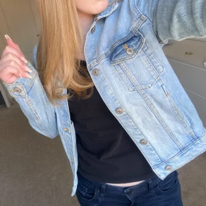 Ljusblå jeansjacka från Zara - Säljer en snygg ljusblå jeansjacka från Zara. Jackan har en klassisk design med knappar framtill och två bröstfickor med lock. Perfekt för vår och sommar!