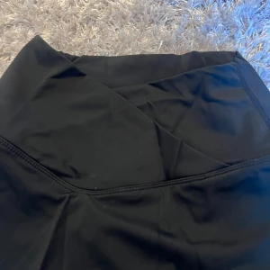 Svart kjol med inbyggda shorts - Snygg svart kjol med inbyggda shorts, perfekt för en aktiv livsstil. Kjolen har en omlott-design och är gjord i ett stretchigt material för extra komfort. (Aldrig använd men har legat i en låda ett tag, pris kan diskuteras)